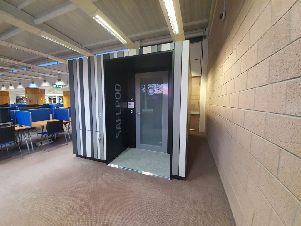Grey panelled exterior of the SafePod room with vestibule area containing frosted glass door and SafePod lettering